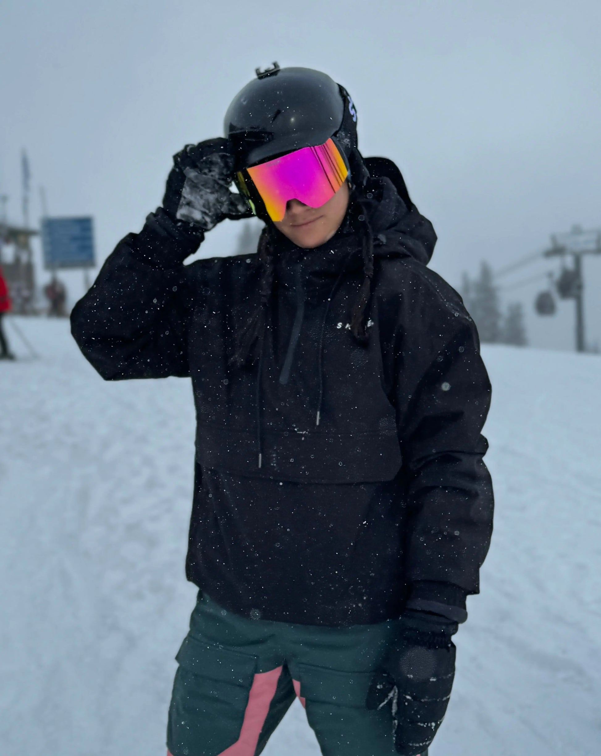 a woman in a black jacket and goggles on a ski slope